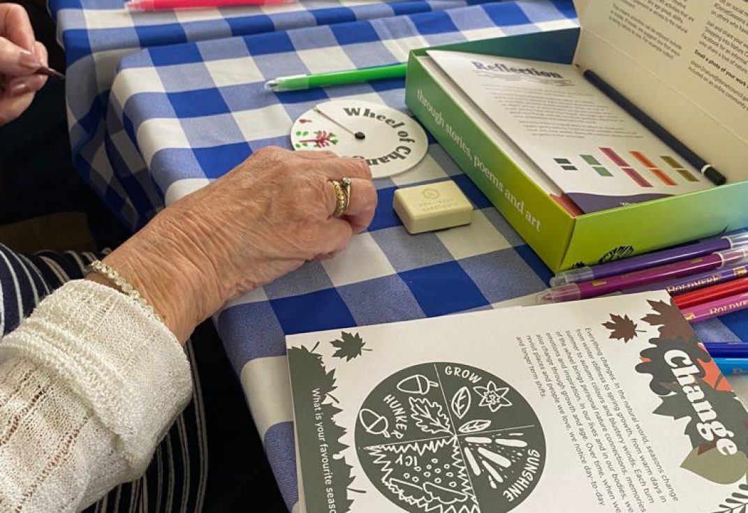 An older person's hands doing art and crafts at a table from the Your Seasons of Stories pack