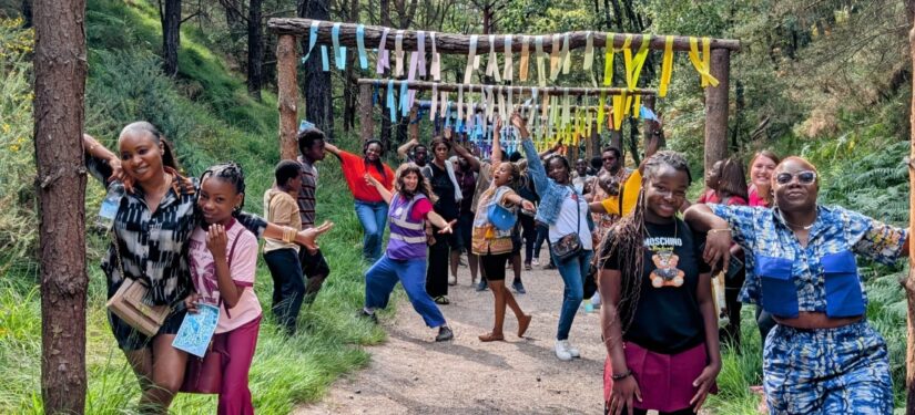 Group of people posing at the Blue Pool under a tunnel of colourful streamers.