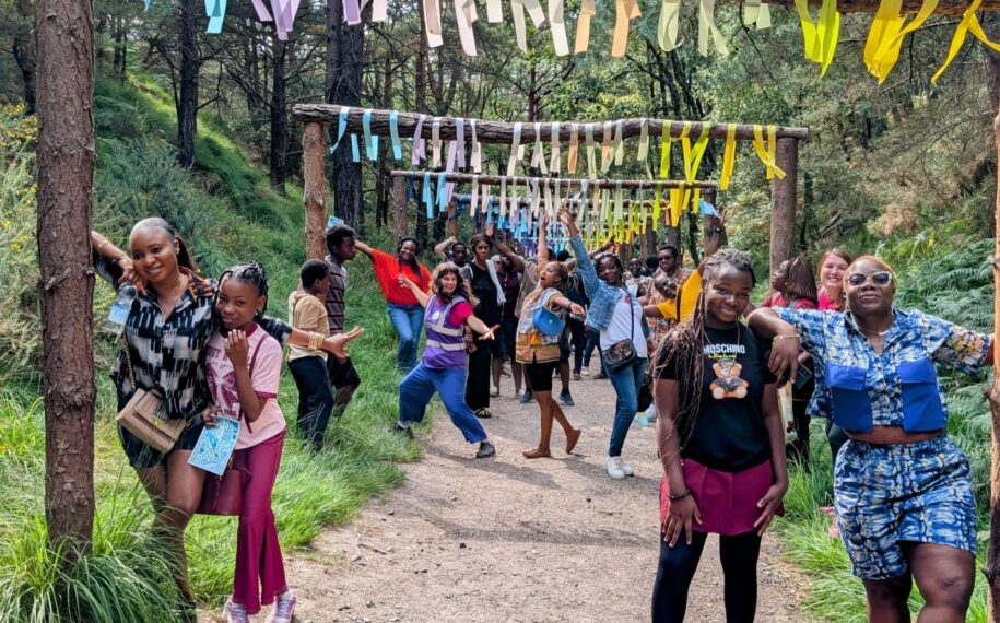 Group of people posing at the Blue Pool under a tunnel of colourful streamers.
