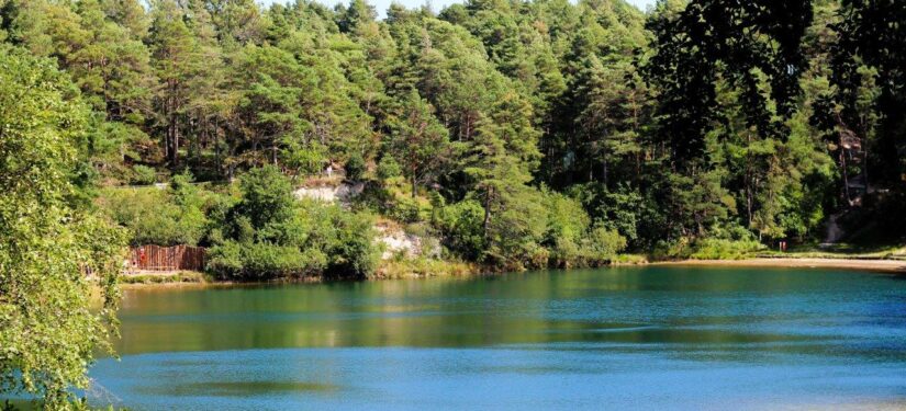 Turquoise lake reflecting the sky with a backdrop of green woodland