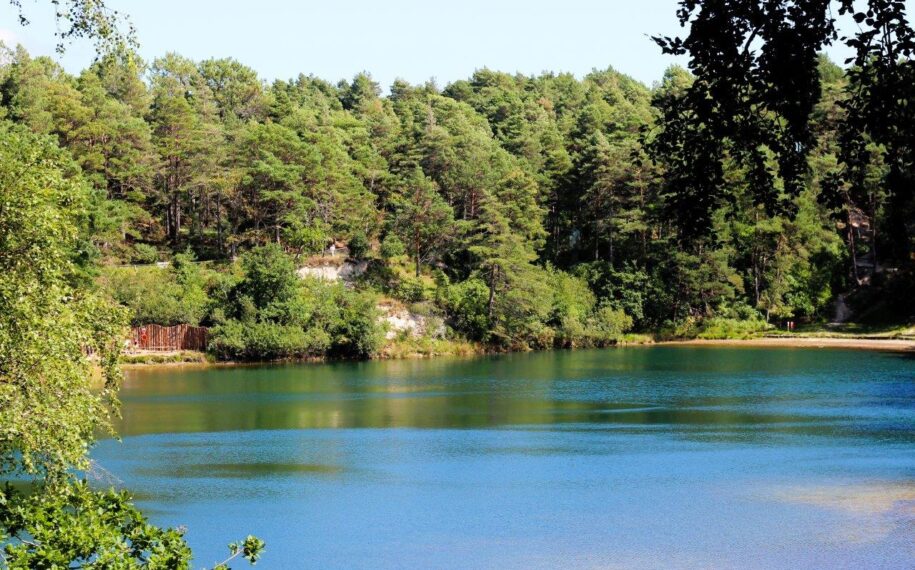 Turquoise lake reflecting the sky with a backdrop of green woodland
