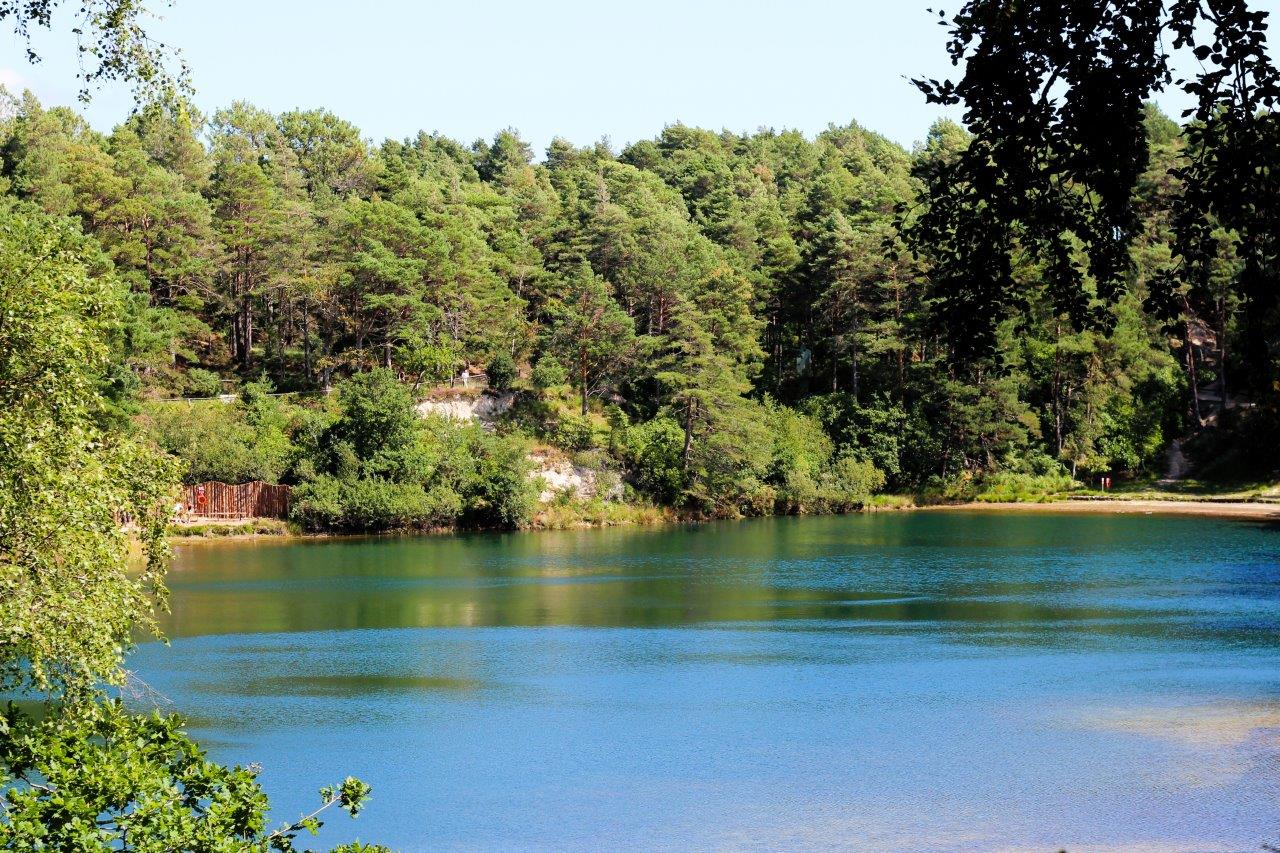 Turquoise lake reflecting the sky with a backdrop of green woodland