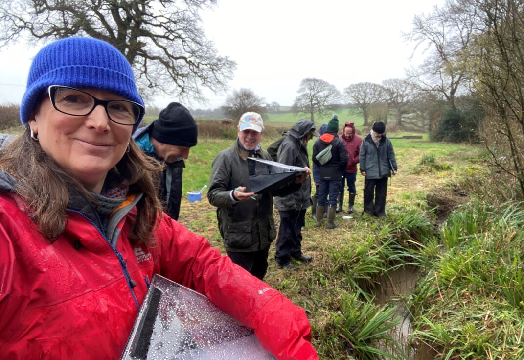 A group of people surveying a riverbank in the rain
