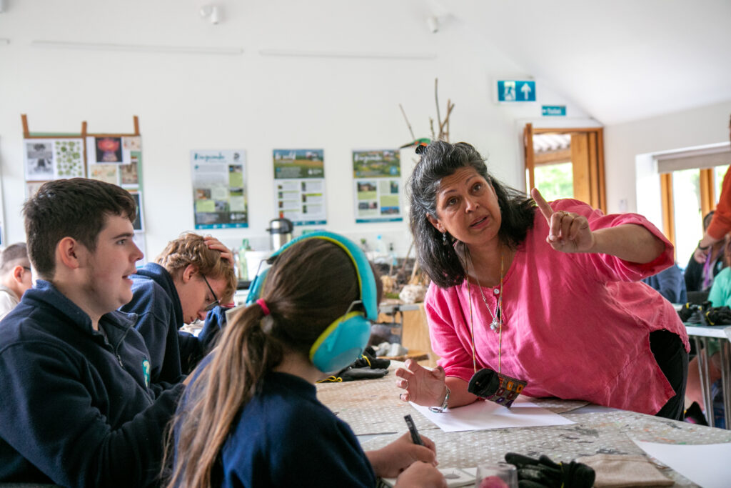 Room with people drawing with women in pink shirt pointing to something on the wall