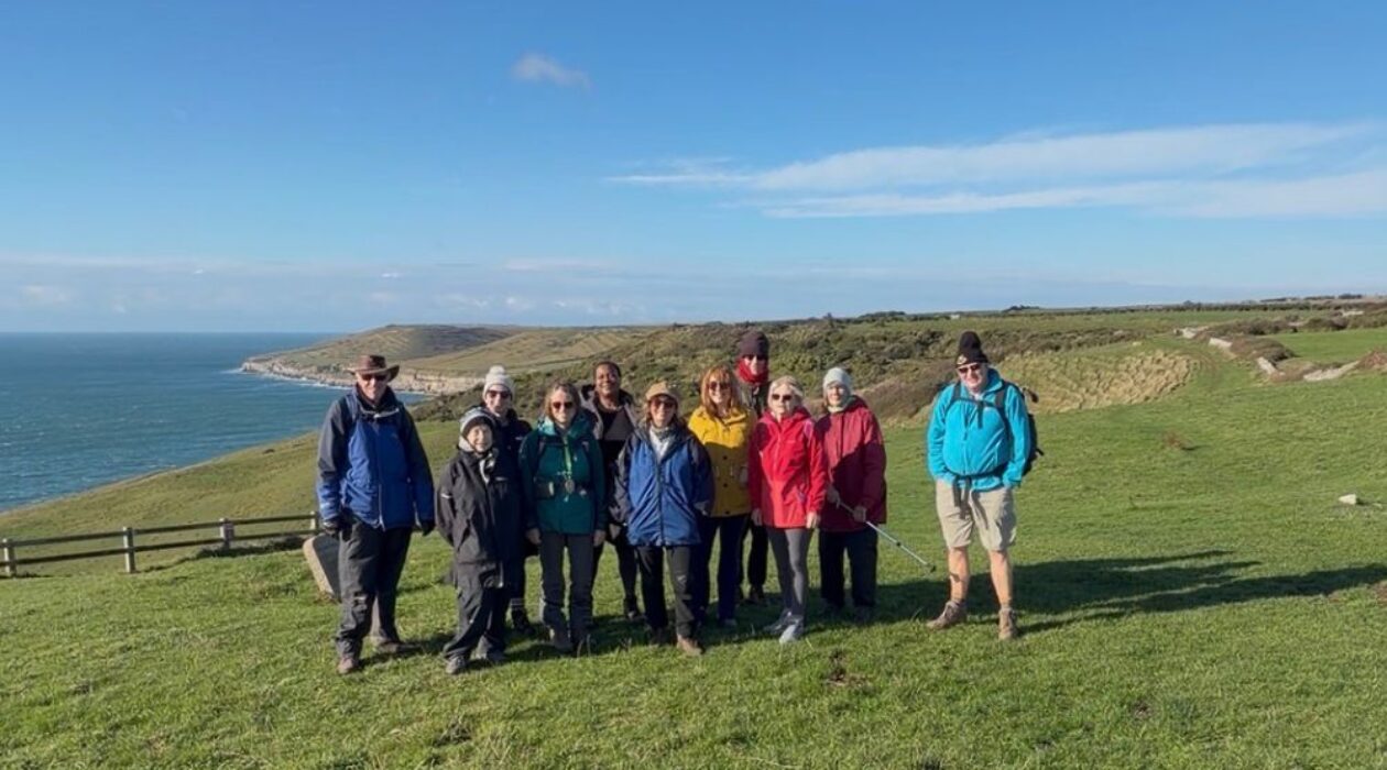 A group photo of walkers on the coast path with the sea in the background on a bright winters day.