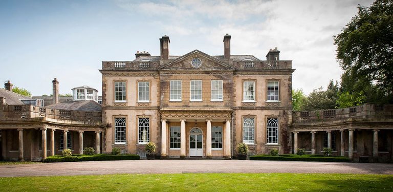 a large country house with grass in the foreground