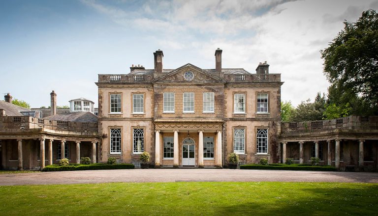 a large country house with grass in the foreground