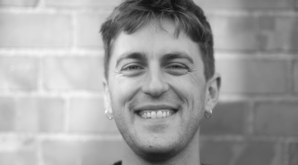 Full face shot of a man smiling, with brick wall in background